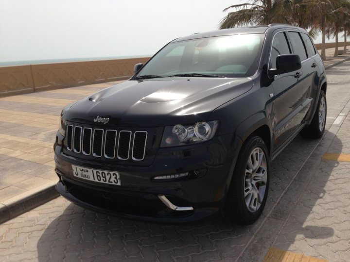 New to Dubai - Saying Hi - Page 1 - Middle East - PistonHeads - The image shows a black Jeep parked by the roadside. The vehicle is an SUV and has a modern design with a license plate visible on the front. The car is situated on a cobblestone street, suggesting the location is urban or suburban. In the background, there are palm trees, which might indicate a warmer climate. The sky is clear, suggesting that the photo was taken on a sunny day.