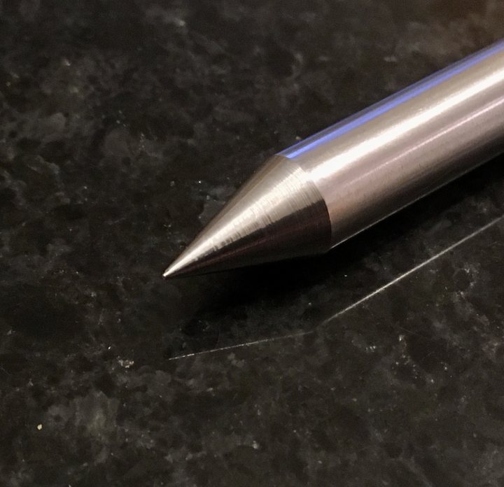 A pair of scissors sitting on top of a table - Pistonheads - The image shows a silver-colored pen resting on a dark surface. The pen is positioned vertically, with the nib pointed downwards towards the bottom of the frame. The writing tip is clearly visible and appears to be in good condition. The background provides a stark contrast to the pen, highlighting its metallic color. There's no text or other objects present in the image. The focus is solely on the pen, suggesting that it might have some significance or importance.