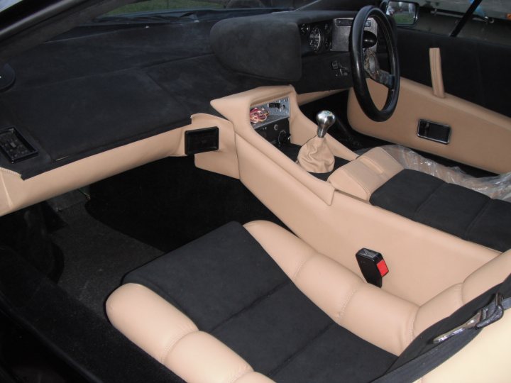 Pistonheads - The image shows the inside of a luxury car with a focus on the mock sunlight on the beige leather seats. The steering wheel is visible, indicating that the car is empty and no one is driving at the moment. There is a small black rectangular item on the front passenger seat, which stands out against the light beige upholstery. The car is in a showroom or a dealership, possibly waiting for a prospective customer.