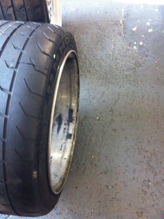 A black and silver motorcycle parked on a street - Pistonheads - The image shows a single car tire with tread visible on a cement surface. The tire is close to the ground and appears somewhat worn. There is no visible text or branding on the tire or its rims. The background is mostly indistinct but suggests an external environment with a concrete floor. The overall style of the image is a straightforward realism photograph, possibly meant for inspection or documentation purposes.