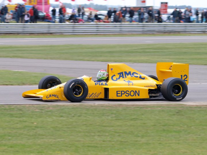 Pistonheads Snetterton - In the center of the image, a vibrant yellow racing car speeds down a race track. The car is marked with the number 12 and the word "EPSON," indicating it's part of a professional racing event. The number 12 suggests the car might be participating in a qualifying session or a race where the grid is ordered by a random draw.

The car is designed with aerodynamic features, enhance its performance on the track. The word "EPSON" is prominently displayed on the side of the car, and the number 12 is visible in the background, possibly on the car's wing, hinting at a sponsorship deal with the company.

In the background, a crowd of spectators watches the car's progress, adding to the intensity and excitement of the event. Above, the sky is clear and blue, making it a perfect day for racing.