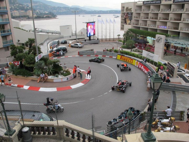 A group of people walking down a street - Pistonheads - The image captures an exciting scene from a go-karting event. Multiple go-karts, each a different color, weave through a winding track complex involving banked turns and chicanes. The racers are dressed in casual racing attire and are leaning into the curves as they navigate the challenging course. The background reveals a large body of water with boats floating on it, and buildings that suggest the area might be a waterfront or resort-style location.