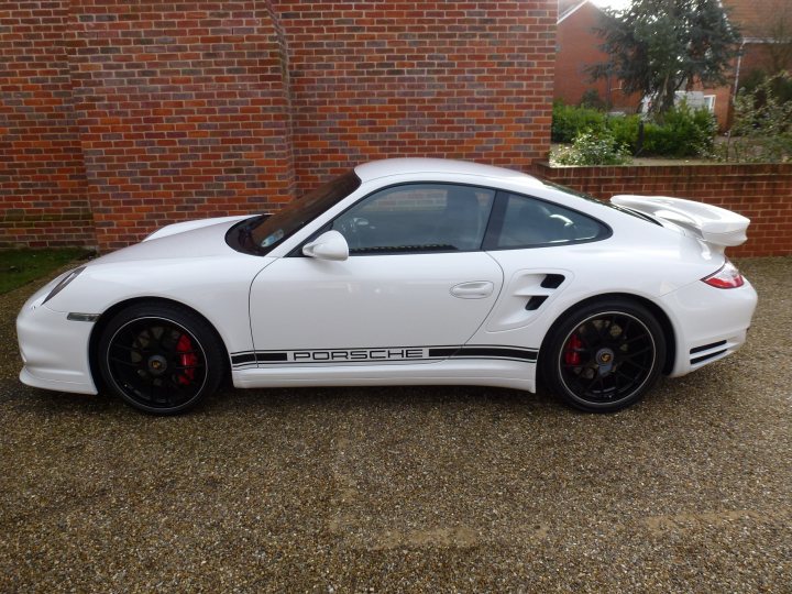 Belated Xmas Cheer (aka Ultima Replacement) - Page 1 - East Anglia - PistonHeads - The image shows a white Porsche parked on a gravel driveway against a backdrop of a brick wall. The car is a Convertible with a power topped roof and black wheels. The B-Series engine is visible with the car hood open, indicating possible maintenance or a showcase of the engine. The overall setting suggests a private residence, as there are no visible tourist attractions or signs indicating a public location.