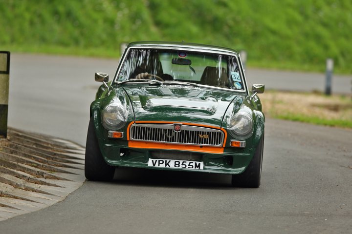 A car is parked on the side of the road - Pistonheads - The image captures a moment on a winding road. At the center of the frame is a racing car, painted in a striking shade of green. The car is in motion, ripping around a turn, its orange stripe flashing against the green.

The car's angle and speed create a sense of motion and excitement. The background of the image reveals a grassy hillside, with the road curving towards it. The contrast between the urban-racing vibe of the car and the natural, serene backdrop adds a dynamic element to the scene. The image does not contain any text.