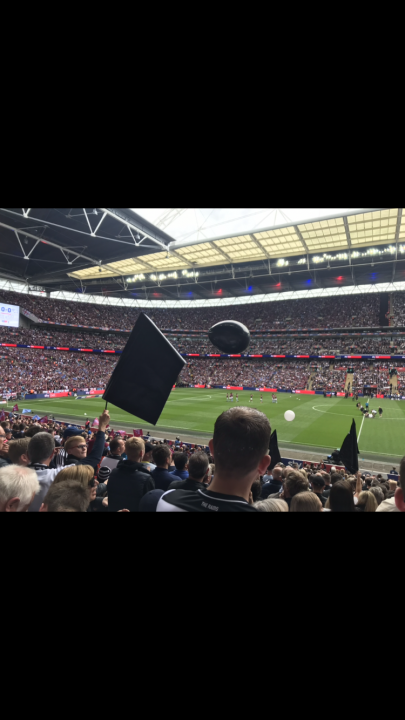 The Official Derby County Thread - Page 4 - Football - PistonHeads - The image captures a vibrant scene at a soccer match. A crowd of spectators, engrossed in the game, fills the stands. The stadium seats are predominantly black and white, with some sections showing signs of activity. The field is a lush green, contrasting beautifully with the gray sky. Above, black and white flags flutter proudly, adding to the festive atmosphere.