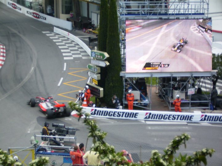 Pistonheads - This image captures a thrilling scene from a Formula 1 race. The track, adorned with safety barriers, is flanked by spectators on both sides. In the midst of the action, a speeding race car is in the lead, surrounded by other racers. Huge screens and advertising billboards can be seen lining the track, adding to the spectacle of the race. The image encapsulates the intensity and excitement of the sport.