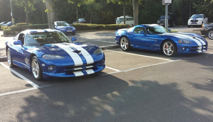 Not one but two... - Page 1 - Vipers - PistonHeads - The image showcases a parking lot occupied by several blue cars, all identical in appearance. These cars are parked in spots marked with white lines, indicating a well-organized parking area. In the background, there are vehicles and trees, suggesting that the parking lot is in a suburban or public area. The location appears to be a public parking area, possibly near a business or residential complex, given the density of parked cars. The overall scene conveys a sense of order and safety, with the marked spots and parked cars suggesting that the area is monitored for parking regulations.