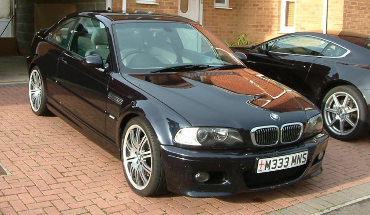 Detailed Motor Lucky Pistonheads Luciano - The image captures a scene on a sidewalk with two cars parked. A sleek black BMW car is the main subject, parked on the left side of the image. The car has alloy wheels and a black sunroof. On the right side of the image, there is another car, although its make and model are not fully visible. The cars are positioned beside each other, suggesting a shared interest in automobiles or simply coexisting in a parking lot. This composition gives a sense of a moments pause in a busy urban setting.