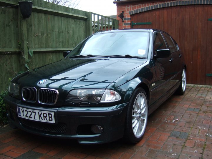 Pistonheads Midlands Newbie - The image shows a BMW car parked on a brick driveway next to a wooden gate. The car is black and polished, suggesting that it is well-maintained. The license plate on the car reads "Y22 KRB," indicating it is from the United Kingdom. The gate behind the car is made of wood and has a green trim, providing a contrast to the red brick driveway. The setting appears to be suburban, as there is another house visible in the background, and the weather seems to be cloudy.