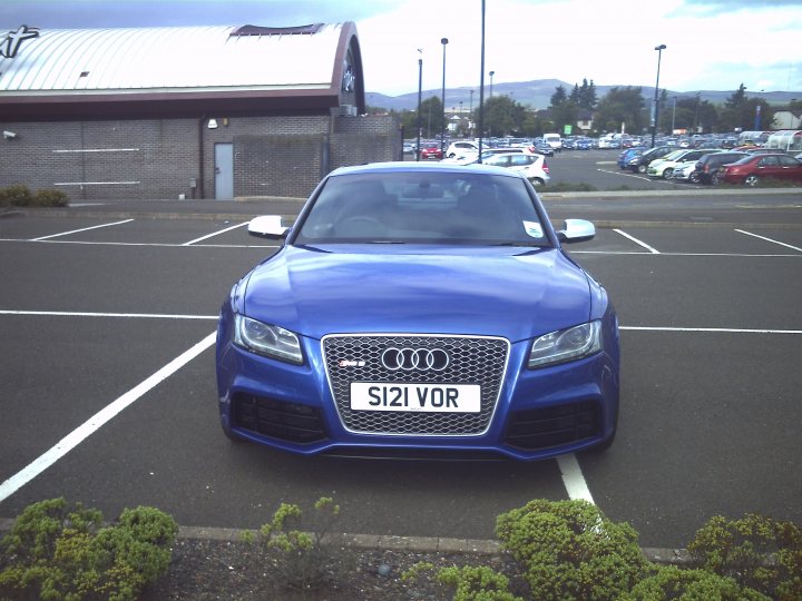 Scotland's Finest Spotted!! [Vol 2] - Page 9 - Scotland - PistonHeads - The image features a striking blue Audi car prominently positioned in the foreground of a parking lot. The car's front license plate reads "SK12 VOR", indicating a European-style plate. The backdrop of the parking lot is filled with other parked cars, hinting at a busy location. Above, the sky is filled with clouds, suggesting an overcast day. Despite the overcast weather, the vibrant color of the Audi car adds a splash of brightness to the scene.