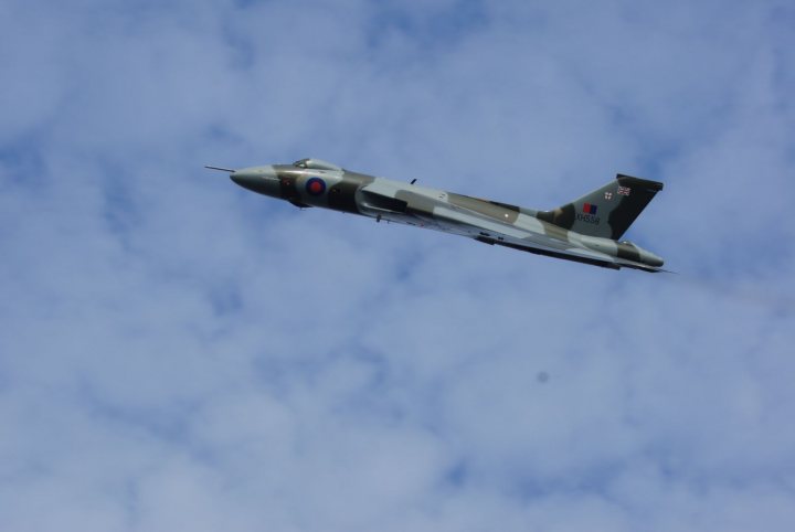 A fighter jet flying through a blue sky - Pistonheads - The image captures a moment of a fighter jet in action. The aircraft is a UK military plane, identifiable by its distinctive grey and green camouflage. It's soaring through a clear sky, leaving behind a trail that slightly contrasts with the bright blue above. The plane is off to the side, giving a sense of motion and speed. The jet's presence in the sky adds a sense of power and dynamism to the scene.