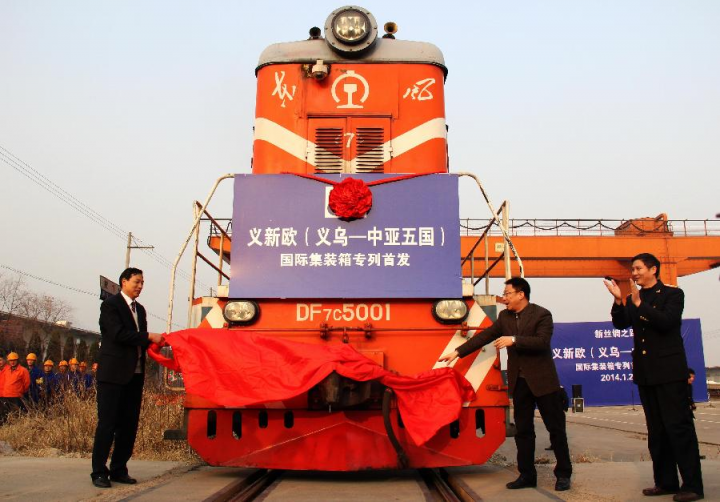 A red double decker bus driving down a street - The image depicts a vibrant scene at a train station. A red and white train, which is the main focus of the photo, is adorned with various flags, including one that prominently displays the Chinese flag. A group of individuals, possibly workers or officials, are standing in front of the train, ready to welcome it. They are holding a banner that reads "Welcome to the new line," signifying an event related to the launch of a new railway route. The backdrop of the image reveals a clear sky and an expansive train track, emphasizing the scale and importance of this moment.