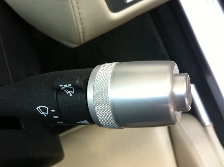 Pistonheads - The image provides a close-up view of the center console of a car, focusing on the gear shift lever and its surrounding area. The gear shift is black with a silver, metallic lever that seems to be made of metal, possibly steel or aluminum. Atop the lever, there are two white buttons, each accompanied by a black line. The leverage cap is silver, with a prominent cutout for the lever to pass through. The image gives the impression of a modern, high-quality interior with attention to detail in design and materials.