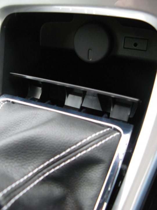 Pistonheads - The image shows the interior of a glove compartment of a vehicle. The glove compartment has a black finish and features a sleek design with white trim along the edges. Inside, there appears to be a small compartment with a lever, and two shelves have been installed under it for organizing items. The main part of the compartment is likely intended for documents, phone cases, or other small items, and is lined with a black fabric that contrasts with the surrounding area.