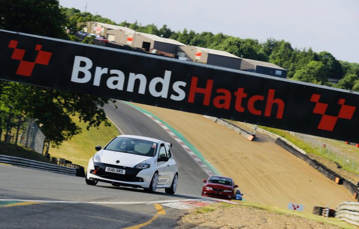 MrTouring car history and current e61 M5 and 944 - Page 8 - Readers' Cars - PistonHeads - The image is a photograph taken at a racetrack during what appears to be a professional race. In the foreground, there's a sign that reads "BRANDS HATCH," indicating that this is likely the Brands Hatch circuit, known for its motor racing events. In the background, we see cars on a race track with a greenish-yellow hue, suggesting it might be a specific type of racing. The sky is overcast, and the setting seems to be a daytime event.