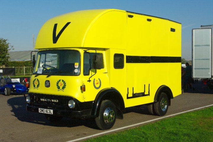 breakfast club sunday october 2 - Page 1 - Goodwood Events - PistonHeads - In the center of the image, a large, vivid yellow Vespa transport truck is parked. The truck is adorned with a yellow leaf on the driver's side, a distinctive feature of the Vespa brand. The vehicle also bears a "Cofle" emblem, suggesting some affiliation with that entity. The truck is parked on a grassy area, adjacent to a path. In the background, there are other vehicles, possibly part of a car show or similar gathering.