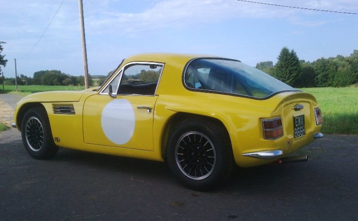 Early TVR Pictures - Page 35 - Classics - PistonHeads - The image depicts a bright yellow vintage car parked on the street. The car has a distinctive round emblem on the side, and its shiny exterior reflects the sunlight. It features black wheels and a distinctive license plate that reads "LKM 698". The vehicle appears to be well-maintained, suggesting it might be the owner's pride and joy. The photograph is taken during the day under a clear sky, creating a vibrant and cheerful atmosphere that compliments the car's vibrant color.