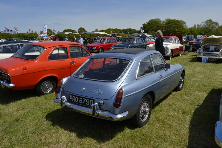 1966 MGB GT - stolen - please help! - Page 1 - MG - PistonHeads - The image showcases a vibrant scene from a car show, brimming with a variety of vintage cars. An orange convertible catches the eye, positioned in the left half of the image. It's a standout with its top down, showcasing a lavish interior that contrasts with its classic exterior. 

In the right half of the image, a sleek blue coupe holds court. This car's glossy finish stands out against the backdrop of other vintage cars, drawing the viewer's attention with its classic design. 

These cars are parked in neat rows on a lush, grassy field. In the background, a smattering of spectators mills about, their attention captivated by the array of vehicles on display. The open sky and the abundance of trees in the background lend an air of serenity to the scene. The glory of these vintage cars is undoubtedly the star of this car show.