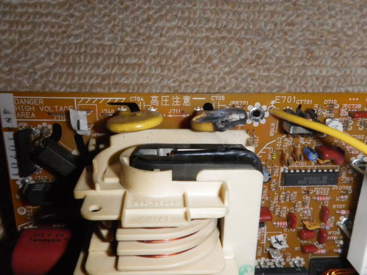 Pistonheads Completely - The image shows the interior of an appliance, likely a household electronic item. Visible are several electronic components, including a control panel with a series of buttons, a electronically operated valve which suggests this could be a pilot light housing, a timer, and a red wire leading to a white power cord. The device appears to be unplugged and is covered in various configurations of wire, possibly indicating maintenance, repair, or testing. The background is white, likely a wall, which contrasts with the beige carpet on the floor.