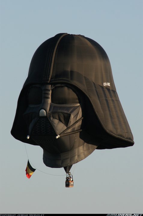 Weirdest Pistonheads Plane - This image features an impressive hot air balloon designed to resemble the face of the iconic character, Darth Vader from the "Star Wars" franchise. The balloon is monochromatic, presenting a darker color palette, and it occupies the entire frame, creating a powerful visual of a film element transformed into an airborne spectacle. The Darth Vader face is prominently displayed on the balloon, showcasing the character's distinctive metal helmet and mask. The balloon is appropriately sized, suggesting it's a lead celebrity balloon, often used to draw attention in parades and festivals. The blue sky in the background contrasts with the dark color of the balloon, enhancing its visual impact. This image captures the magic and creativity involved in balloon sculpture.