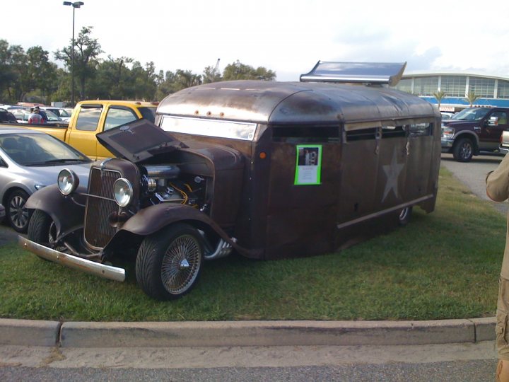 Pistonheads - The image captures a scene on a road where an old, brown, camper-style vehicle with a star logo sits prominently on the side. The vehicle's hood is up, revealing the engine beneath it and potentially suggesting a breakdown or maintenance work. The vehicle is parked near other vehicles, including trucks and a car, indicating a busy or commercial area. It's a bright day, as suggested by the shadows under the vehicles and the clear visibility of the scene. The road stretches ahead, perhaps filled with more vehicles, and there's a glimpse of a building in the distance.