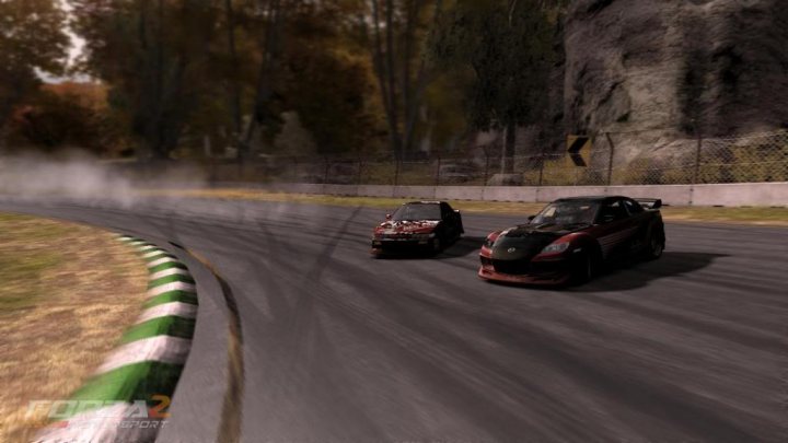 Forza Queries Pistonheads Drifting Sliders - The image captures a dynamic scene of a race car track. Two cars are racing simultaneously, one taking the lead. They are rounding a bend on the track, their tires hugging the turns. The track itself is situated amidst a scenic landscape of trees and a backdrop of a rocky cliff. The entire scene exudes the thrill and speed of the sport.