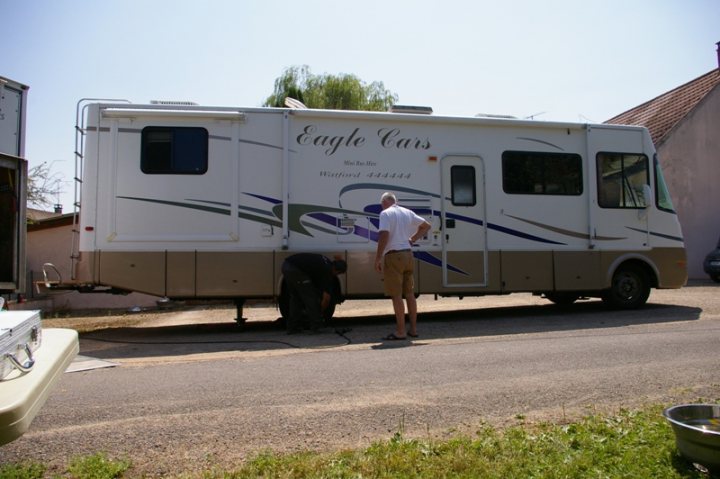 Old tyres - Page 1 - Tents, Caravans & Motorhomes - PistonHeads - The image shows a man standing beside a large, white recreational vehicle (RV). The RV is parked and appears to be a sports or leisure model given its sleek design and the name "Eagle Cruisers" visible on its side. The man is dressed casually, indicating a relaxed, possibly leisurely, setting. In the distance, there's a car partially visible from behind, and the sky suggests it might be a sunny day.