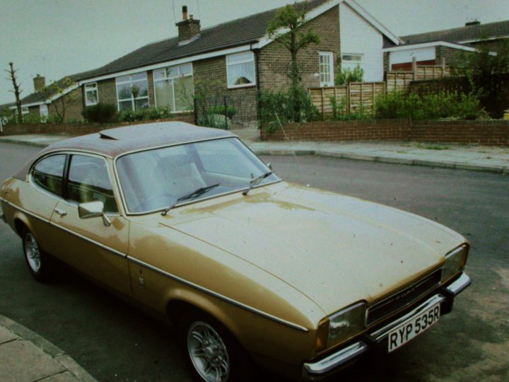 Classics left to die/rotting pics - Vol 2 - Page 339 - Classic Cars and Yesterday's Heroes - PistonHeads UK - The image presents a scene dominated by a large, yellow car parked on the side of a road. The vehicle is quite old-fashioned, adding a nostalgic touch to the photo. The surroundings include a house and a tree in the background, suggesting a suburban setting. Despite being an old photo, it retains a sense of life with its vivid colors and clear details.