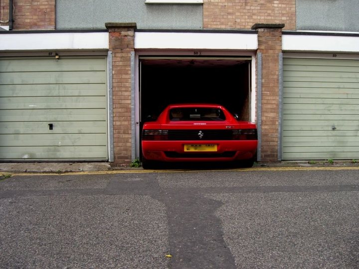 Parking a normal size car in a normal size single garage. - Page 3 - General Gassing - PistonHeads - The image shows a small sports car parked inside an open garage bay. The car is focused on the viewer, appearing ready to drive out of the garage. Its position in the middle of the image leaves the surrounding structure visible on both sides. The garage has a traditional look, with its green and white doors painted and framed in a warm brown tone. The car itself, with its sleek lines and shiny exterior, contrasts sharply with the more muted colors of the garage, drawing the viewer's attention.