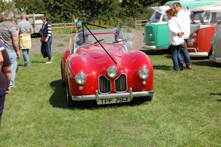 HELP !!!!!! - Page 1 - Classic Cars and Yesterday's Heroes - PistonHeads - The image showcases a red vintage car on display at a car show. The car is a convertible, as suggested by the convertible top that's currently open. The car appears to be an old model, possibly a Triumph, and bears the license plate "TP 793". 

The vehicle is parked near other antique cars, indicating that this is likely a gathering or exhibition of vintage vehicles. Around the car, there are several people standing, presumably attending the car show or admiring the exhibited vehicles.

The scene takes place on a grassy area, which further emphasizes the casual, outdoor setting of the car show. The presence of various people and antique cars suggests a relaxed and social atmosphere. This image captures a moment of appreciation for these classic vehicles and their history.