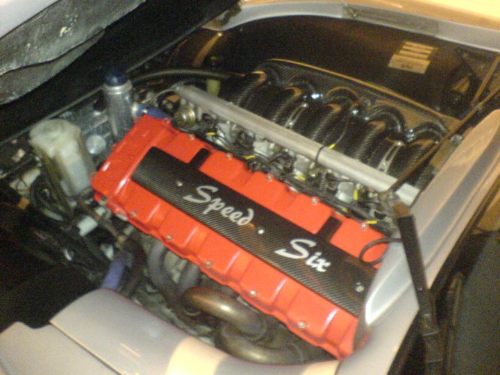 Some pictures of my Tam - Page 1 - Tamora, T350 & Sagaris - PistonHeads - The image shows an under-hood view of a car engine, featuring a large red intake manifold for the accelerator. The engine seems to be a part of a vehicle and extended service manifolds (ESSM) are visible, suggesting an advanced racing engine. The word "Speed6" is prominently displayed on the top of the red intake manifold, indicating the model or make of the engine. The engine itself appears clean and well-maintained, with all hoses, belts, and wires tightly organized and fastened.