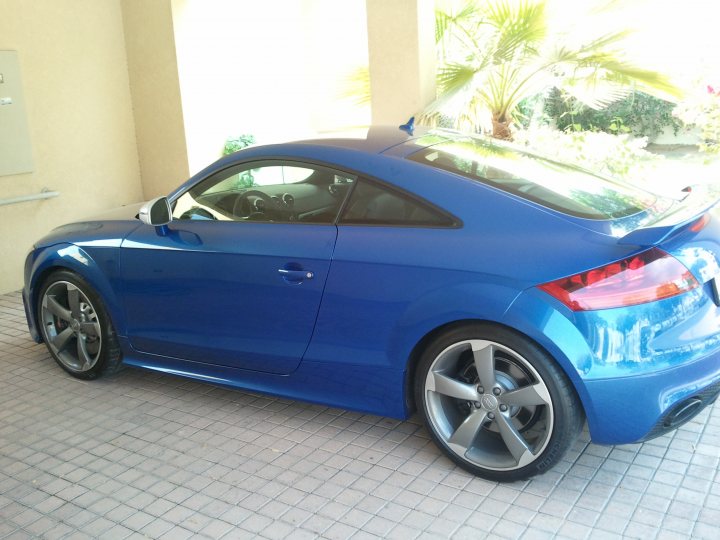 Tuning Pistonheads Ttrs Ecu - The image depicts a blue sports car parked outdoors under the light of day. The vehicle is facing towards the right side of the image, and its sleek design is highlighted by the pronounced contours of the hood and the curved lines of the headlights. The backdrop features a clear sky, a hint of palm trees, and a distant building, suggesting a tropical or Mediterranean location. The car is parked on a paved surface with distinct square tiles, and it seems well-maintained as there are no visible damage or imperfections in its appearance. The image also shows a front view of the car, revealing the design of the front grille and engine cover.