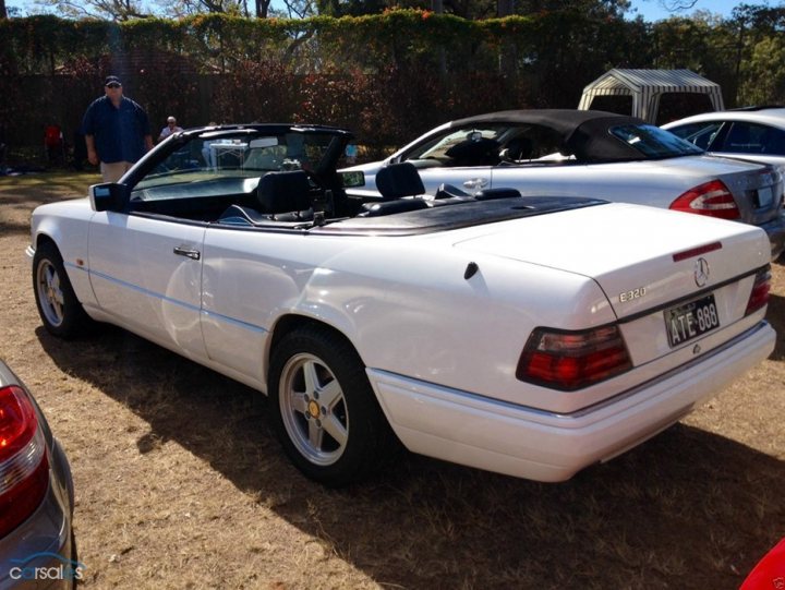 Classic (old, retro) cars for sale £0-5k - Page 134 - General Gassing - PistonHeads - The image features a white Mercedes-Benz car that is topless, sitting on a dirt surface in a lot with several other cars in the background. The topless car has black convertible top rails that contrast with the car's white exterior. It also has a tag that reads "ATE 888" in the back cargo area. The car is parked next to a man who is standing at a safe distance. The overall setting suggests a casual outdoor environment.