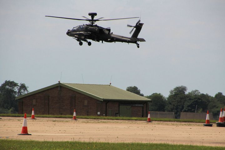 So what have you done with your Aston today? - Page 125 - Aston Martin - PistonHeads - The image depicts a scene of military action. A large military helicopter is captured in mid-air, suggesting it may be taking off or in the process of landing. The helicopter has a dark color scheme, which is typical for military vehicles. It is flying above a runway that is blocked by orange traffic cones, signifying off-limits or restricted access. In the background, there's a structure that seems to be a small building or possibly storage units commonly found at military airfields. The setting is outdoors during the day, as evidenced by the clear sky and open space.