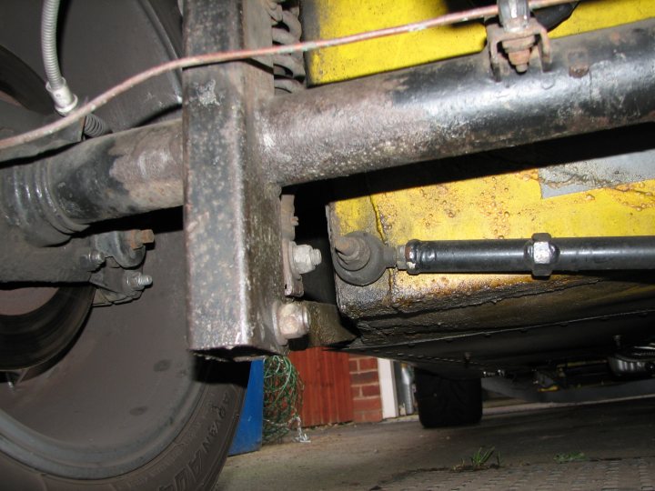 Suspension Pistonheads Play Fury - The image shows a close-up view of the underside of a vehicle, featuring a metallic towing hitch. The hitch is attached to the bumper and serves as a point of connection for towing. It appears to be a part of an older vehicle, indicated by signs of rust and the presence of a cable or cord running through it. The background is out of focus, but it can be deduced that the photo was taken on a street, likely due to the reflective surface beneath the vehicle, which suggests an asphalt road.