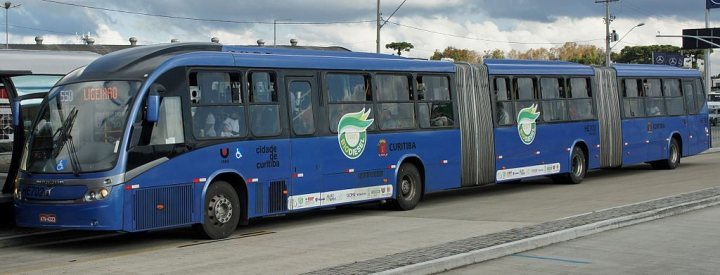A blue and white bus parked in front of a building