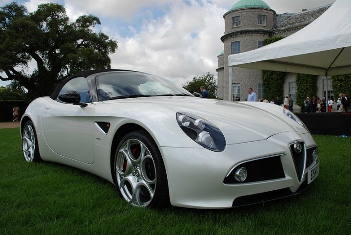 GRRC Lunch Club - Page 1 - Goodwood Events - PistonHeads - The image presents a striking scene, dominated by a pristine white sports car that is parked prominently on a lush, green grass field. The sports car, boasting a sleek and modern design, is facing directly towards the camera, exuding a sense of power and elegance. 

In the blurred background, the silhouette of a stately building, possibly an old castle, adds a touch of historical charm to the scene. Scattered around the vicinity of the car, there are several people, likely attendees at some kind of event or gathering, further hinting at the occasion. 

Overall, the image seems to capture a moment of luxury and elegance at a special event, with the white sports car as the centerpiece amidst the verdant field and the picturesque backdrop of the castle.