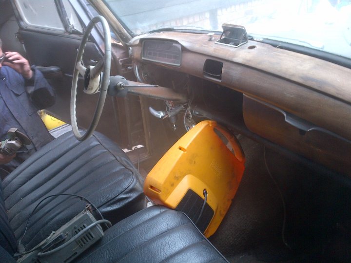 1950's Merc 220s Saved from the grave - rat rod restoration  - Page 1 - Mercedes - PistonHeads - This is an interior view of a well-worn car from the perspective of the passenger seat. Rusted and dirty surfaces are visible, indicating that the car has been inactive for a long time or is poorly maintained. A large, yellow suitcase is placed prominently on the floor in front of the seat, suggesting someone has been traveling or perhaps has just arrived at their destination. The overall atmosphere is gritty and somewhat melancholic. There is also a black windshield wiper on the left side, which is a common accessory for cars.