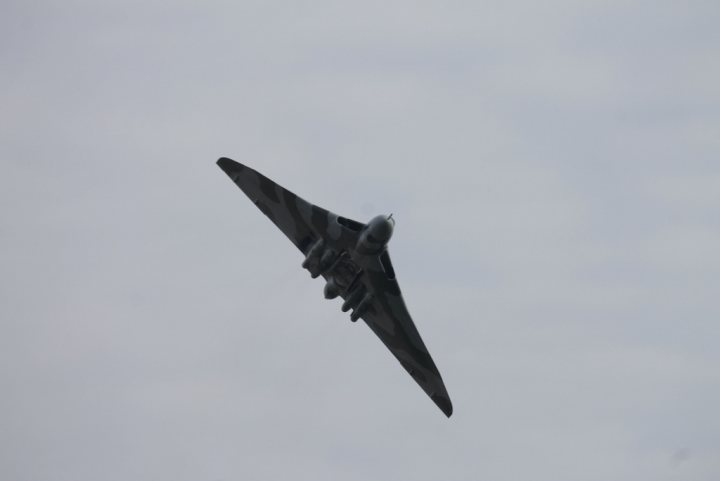 XH558.......... - Page 297 - Boats, Planes & Trains - PistonHeads - The image captures a military fighter jet soaring through the sky. The aircraft, painted in shades of gray, is adorned with black markings across its wings and body. It is equipped with twin engines, visible under the wings, and is positioned in an upward angle, suggesting a fast, high-altitude flight. The background is a vast expanse of cloudy skies, providing a dramatic backdrop to the sleek, efficient form of the jet.