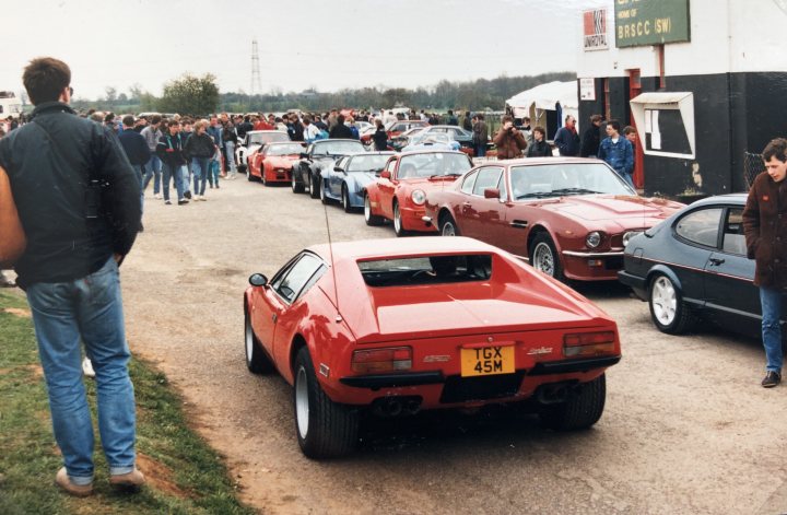 Supercars at Castle Combe, April 1988 - Page 1 - Classic Cars and Yesterday's Heroes - PistonHeads - The image captures a lively scene at a car show. Numerous classic sports cars are parked in neat rows, their polished surfaces reflecting the ambient light. A crowd of enthusiasts is milling about, engaged in conversation and admiring the vehicles. The setting appears to be an outdoor event on a sunny day. Amidst the vintage automobiles, a few modern cars can also be spotted, adding a contrasting element to the scene.