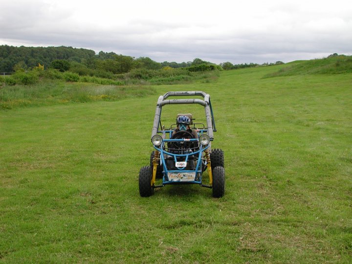 Best off road fun in Scotland - Page 1 - Off Road - PistonHeads - In the image, a person is seated in a blue all-terrain vehicle (ATV) on a serene green grass field. The rider is wearing a blue protective helmet and appears to be in motion, traveling down a path in an open, hilly area. The scene is set against a backdrop of a hazy, gray sky, adding to the tranquil atmosphere. The field is surrounded by an array of trees, indicating that the location might be a rural or forested area. The image captures a moment of leisure or exploration in a natural setting.