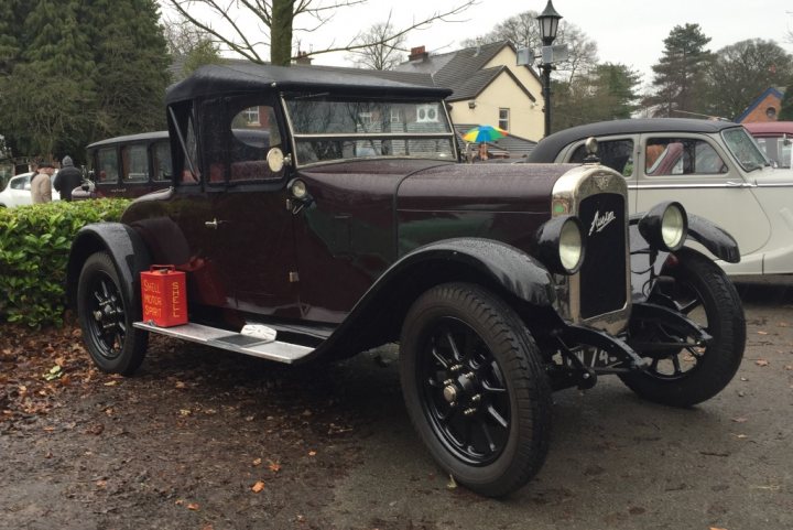 Classic car show Lathom, nr Burscough - Page 1 - North West - PistonHeads - The image shows an old-fashioned vehicle parked on a paved surface. The car, which is dark in color, features a gleaming chrome grill and twin headlamps, embodying a vintage style.