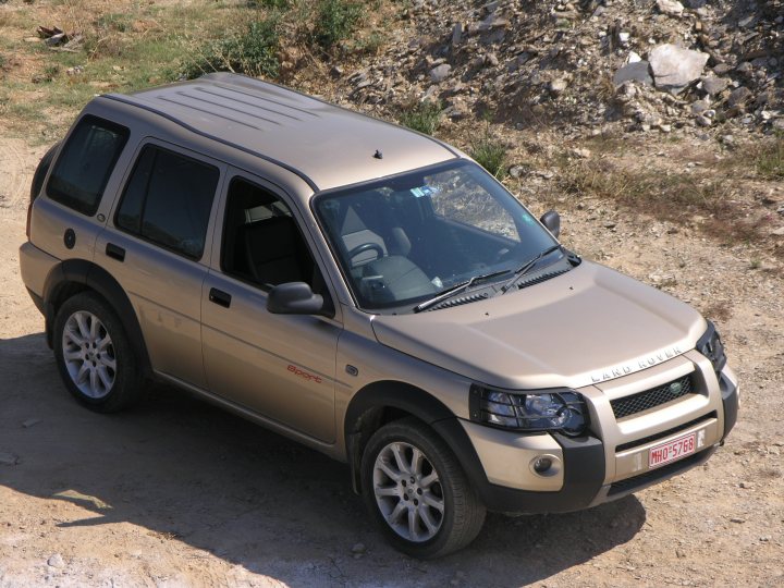 Racing stripes... Let's see 'em!  - Page 1 - Off Road - PistonHeads - The image shows a silver Land Rover parked on what appears to be a dirt ground with scattered rocks to the right. The vehicle is equipped with five-spoke alloy wheels and a bumper guard. It has no visible text or distinguishing marks. The photo is taken during the day with natural lighting. The Land Rover is positioned at a three-quarter angle, showcasing the front and part of the side.