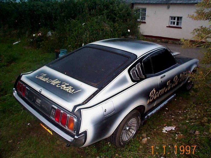 Classics left to die/rotting pics - Vol 2 - Page 185 - Classic Cars and Yesterday's Heroes - PistonHeads - The image shows a vintage car parked on what appears to be a driveway or street. The car has a distinctive silver and black finish, with the top half featuring the word "Phoenix" and the bottom half showing the name "Santa Fe". The vehicle's hood is propped open. In the background, there is a building partially obscured by plants, indicating a residential area. The image appears to be taken during the day under natural light.