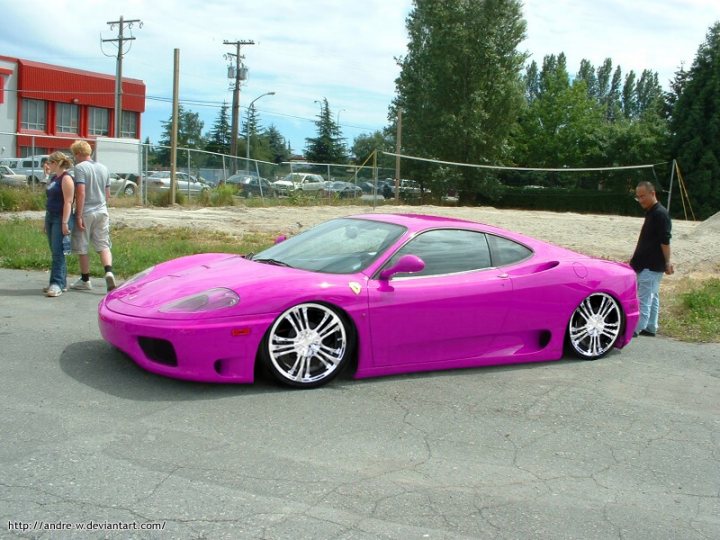 Why own a Ferrari? - Page 1 - Ferrari V8 - PistonHeads - The image features a vibrant pink sports car parked in a lot. The car exhibits chrome rims and a polished front end, suggesting recent maintenance or a visual upgrade. In the background, two people are standing near the car, observing it intently. The setting seems to be a public parking area, as indicated by the multiple utility poles and vehicles in the vicinity. The car's striking color and sleek design draw attention and spark interest among those present around it.