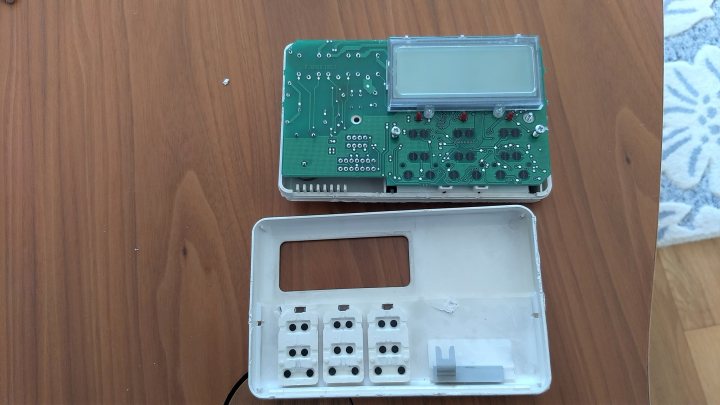 Horstmann heating timer - how to remove? - Page 2 - Homes, Gardens and DIY - PistonHeads - The image captures a close-up view of an electronic device, specifically an open laptop. The device is situated on a wooden table. It appears to be in the process of being assembled or repaired, as indicated by the open casing and exposed internal components.