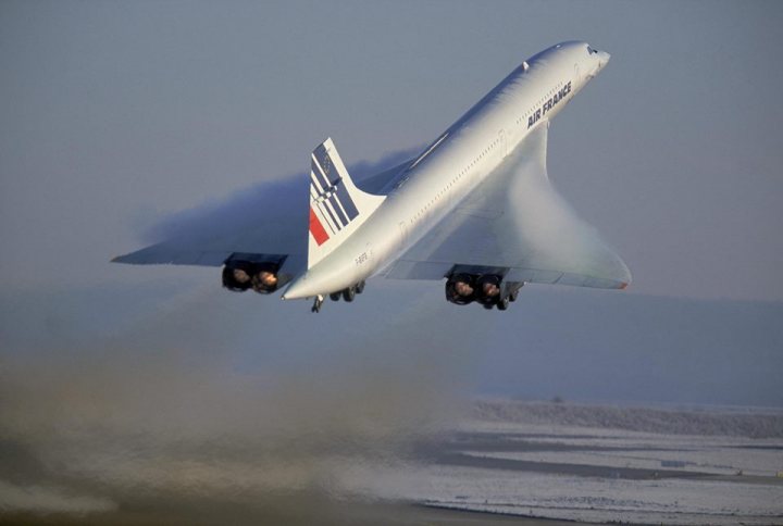 Post amazingly cool pictures of aircraft (Volume 2) - Page 202 - Boats, Planes & Trains - PistonHeads - The image showcases an Air France Concorde taking off, captured from a side angle. The airplane, predominantly white, with red and blue accents, is ascending into a hazy sky. The plane is creating a wake of smoke behind it, accentuating the high-speed takeoff. The ground appears to be a barren landscape, possibly a desert or icy tundra. The absence of other aircraft or people in the vicinity suggests that this might be a test flight or a special event.