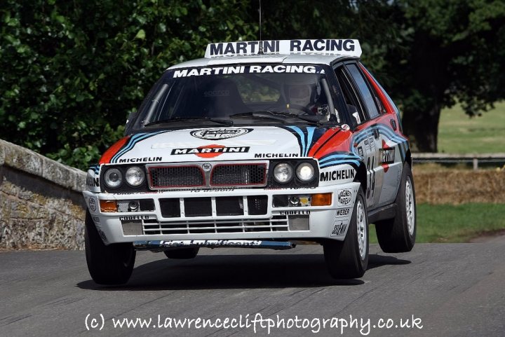 Pistonheads Staffs North Body South Cheshire - The image shows a custom rally car with text and logos, including 'MARTINI' 'MICHELIN', and the word 'RACING'. The car is designed with a red and white color scheme. The vehicle appears to be in motion, presented from the perspective of the rear. There are trees visible in the background, indicating that the scene might take place on or near a roadway. The text '(c) www.laurencecici.com' can be seen at the bottom, suggesting that the image may have been sourced from that domain. The overall style of the image seems to be a candid, real-world photograph capturing the car in a context that might be associated with a racing event or exhibition.