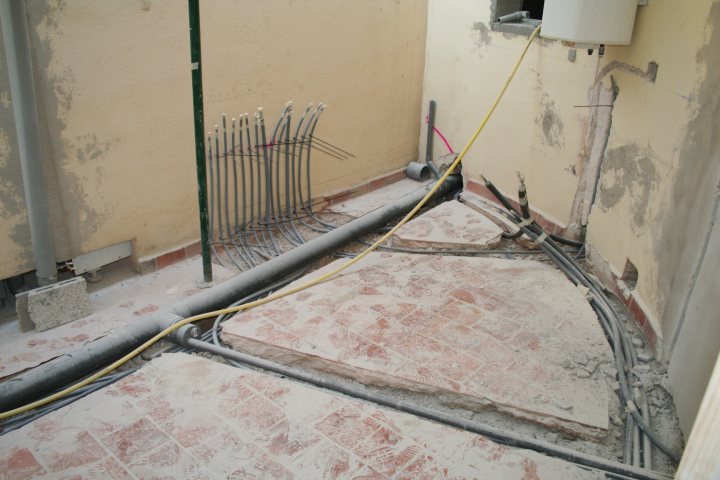 spanish plumbers - Page 1 - Spain - PistonHeads - The image presents an interior view of an unfinished room. The room is under construction, with exposed pipes and wires on the floor and walls. On the center-left side of the room, there is a rack or fixture made from several pieces of metal or pipe fittings, each attached to the ridged border of a low wall or partition. There are also visible pieces of wood planks with a worn-out appearance, indicating the room is in a state of disarray. The room is predominantly empty and lacks any furnishings or decorations. The focus of the image is on the structural elements and the unfinished state of the space.