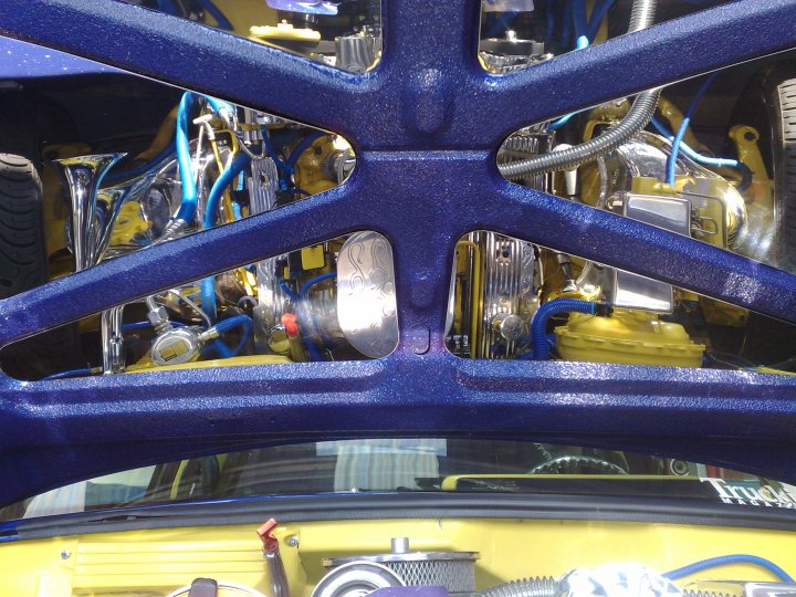 Pistonheads Chevy Truck - The image provides a unique perspective from the engine bay of a vehicle, which is accessible through a back window log for closer inspection of the engine. The view is dominated by a poorly lit, metallic engine with various tubes and connectors clumped together. A complex network of blue and silver hoses and wires intertwines, connecting multiple cylindrical objects, possibly components of the engine. It's a close-up shot showing the intricacies and complexity of the vehicle's mechanical components.